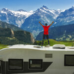 Dieser Outdoor-Abenteurer genießt die atemberaubende Bergkulisse vom Dach seines Campers aus
